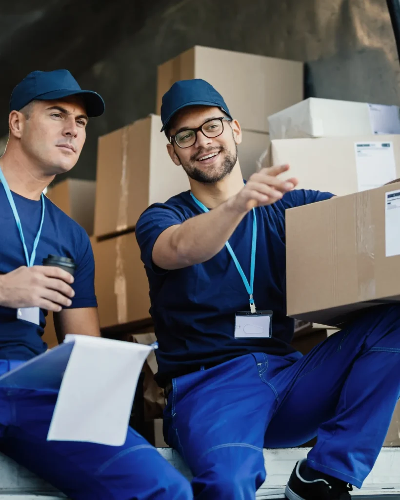 young-courier-pointing-something-while-witting-with-his-coworker-back-delivery-van